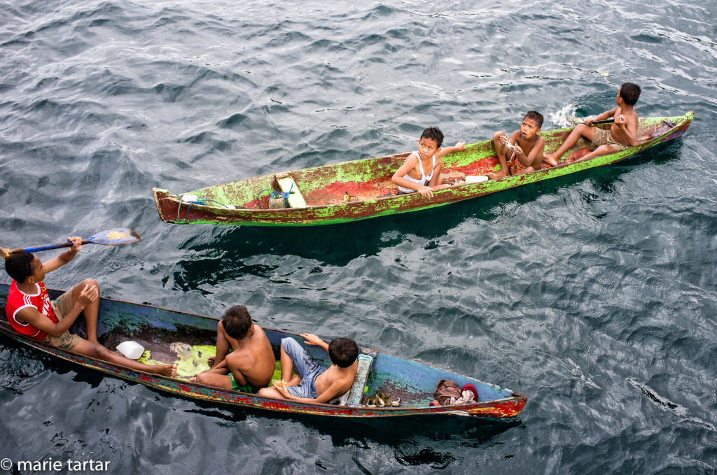 Boys in dugout canoes, Banda Neira, Indonesia