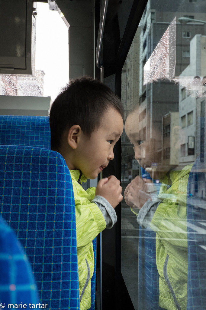 Little boy eyeing his reflection on a Kyoto bus