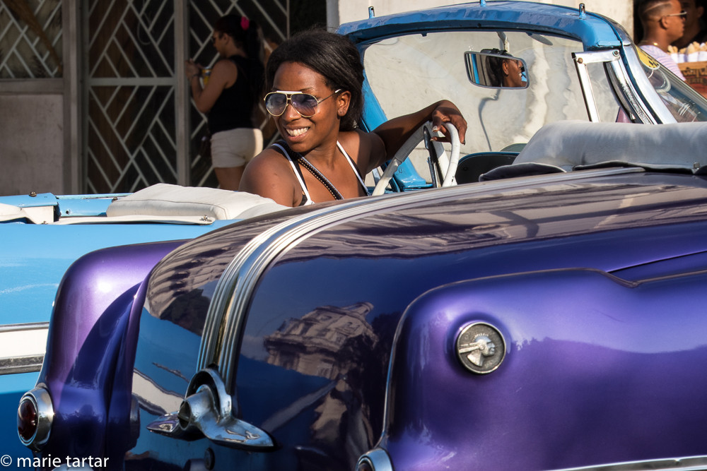 Girl in vintage American 1950s car in Havana