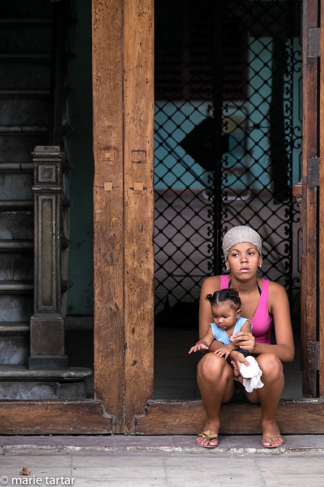 Young mother and child cool off on a stoop in Havana Vieja