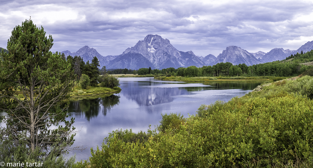 The Tetons reflected in still early water of the Snake River at Oxbow Bend in Grand Teton
