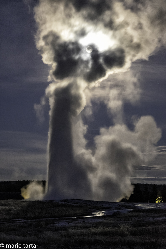 Old Faithful, backlit by a full moon, is the symbol of Yellowstone and erupts roughly every 90 minutes.
